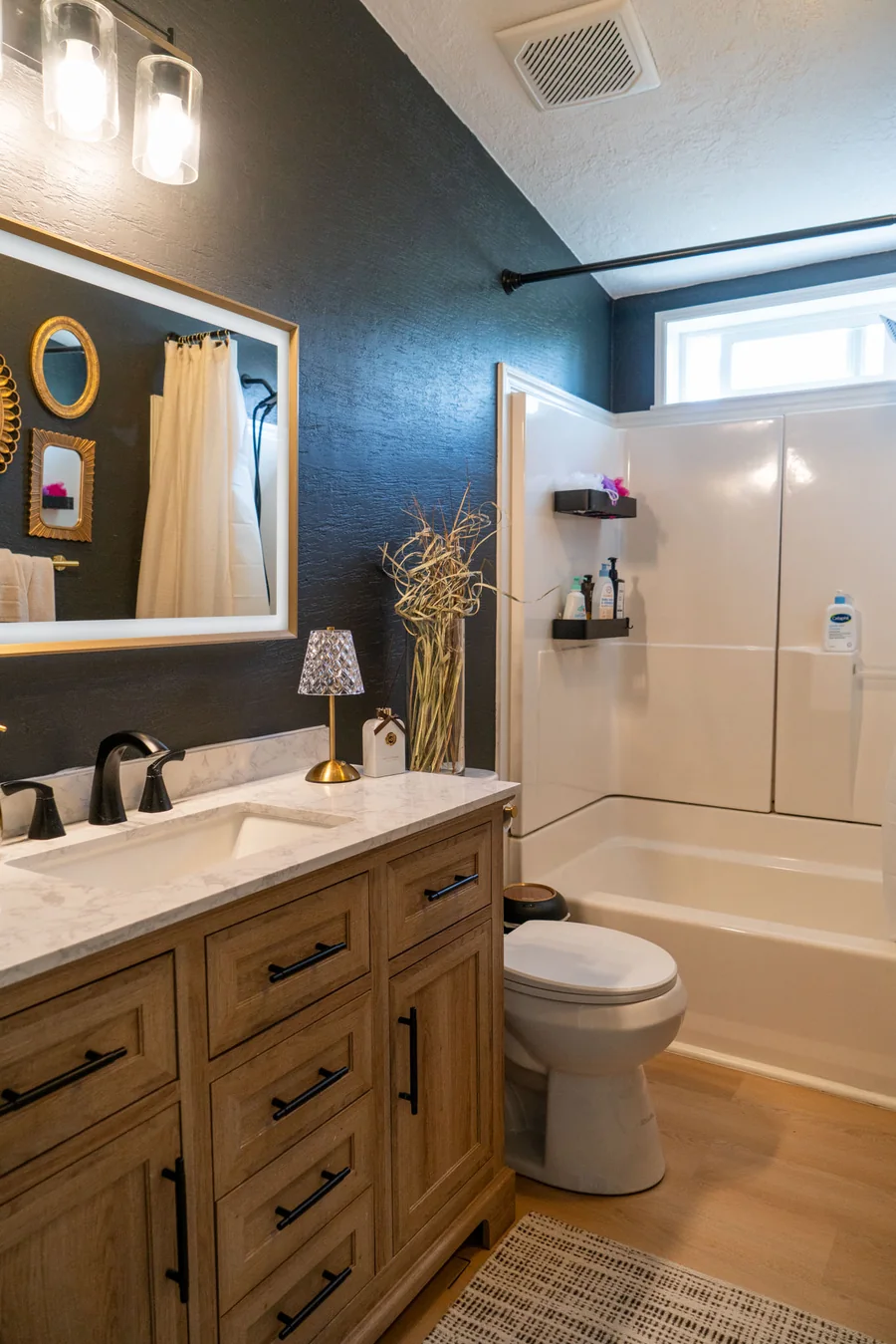 Bathroom finished in deep navy with a white vanity and brass fixtures