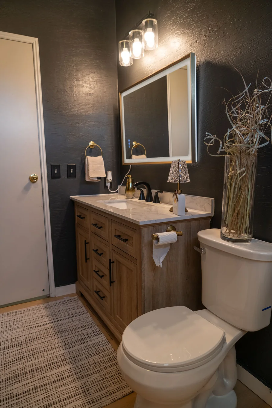 Navy bathroom wall with a framed mirror and sconce lighting