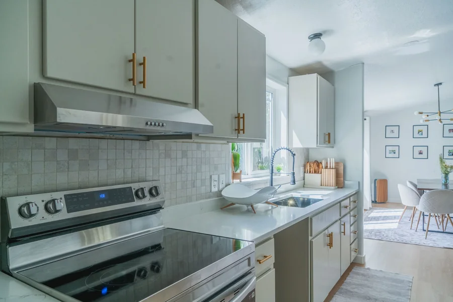 Kitchen cabinetry in white with brass hardware and a tiled backsplash
