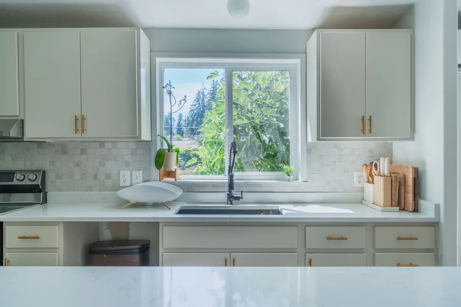 Kitchen window wall with white cabinets and tiled backsplash