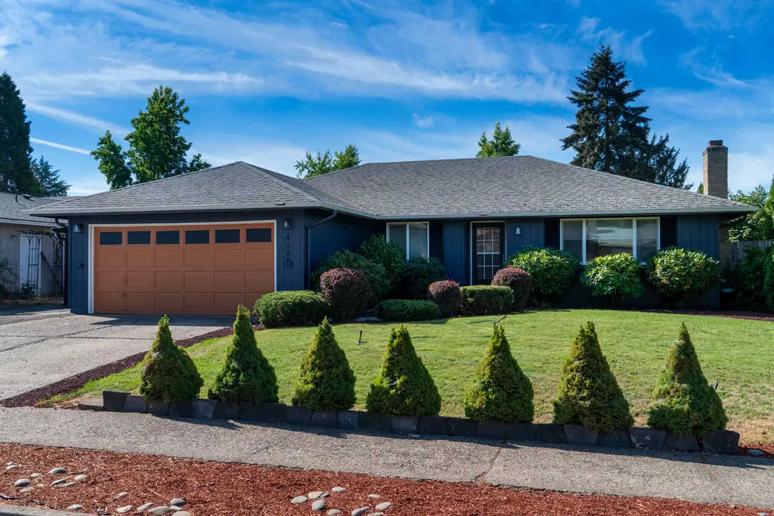 Mid-century ranch after a complete exterior repaint in deep navy with a wood-tone garage door
