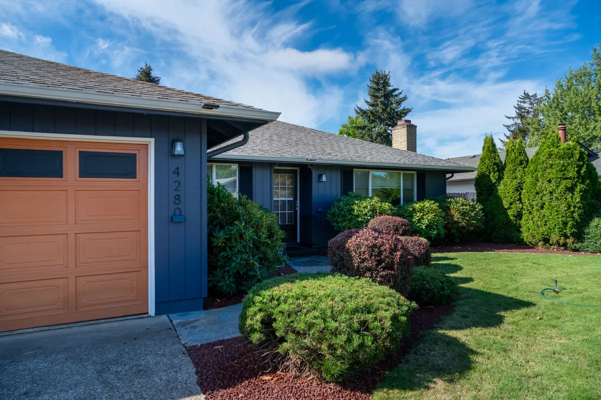 Mid-century Eugene ranch after a complete exterior repaint in deep navy, with a wood-tone garage door