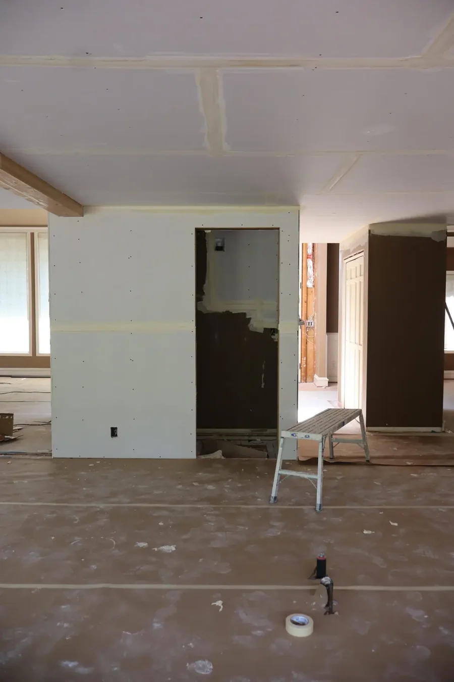 Newly hung drywall in a residential room with the window openings framed out