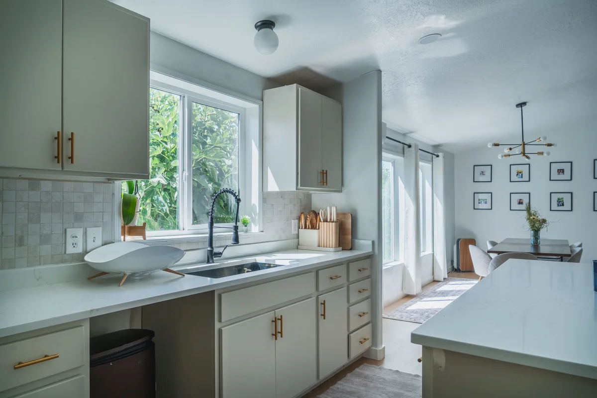 Kitchen and dining area after painting, with white cabinets and brass hardware
