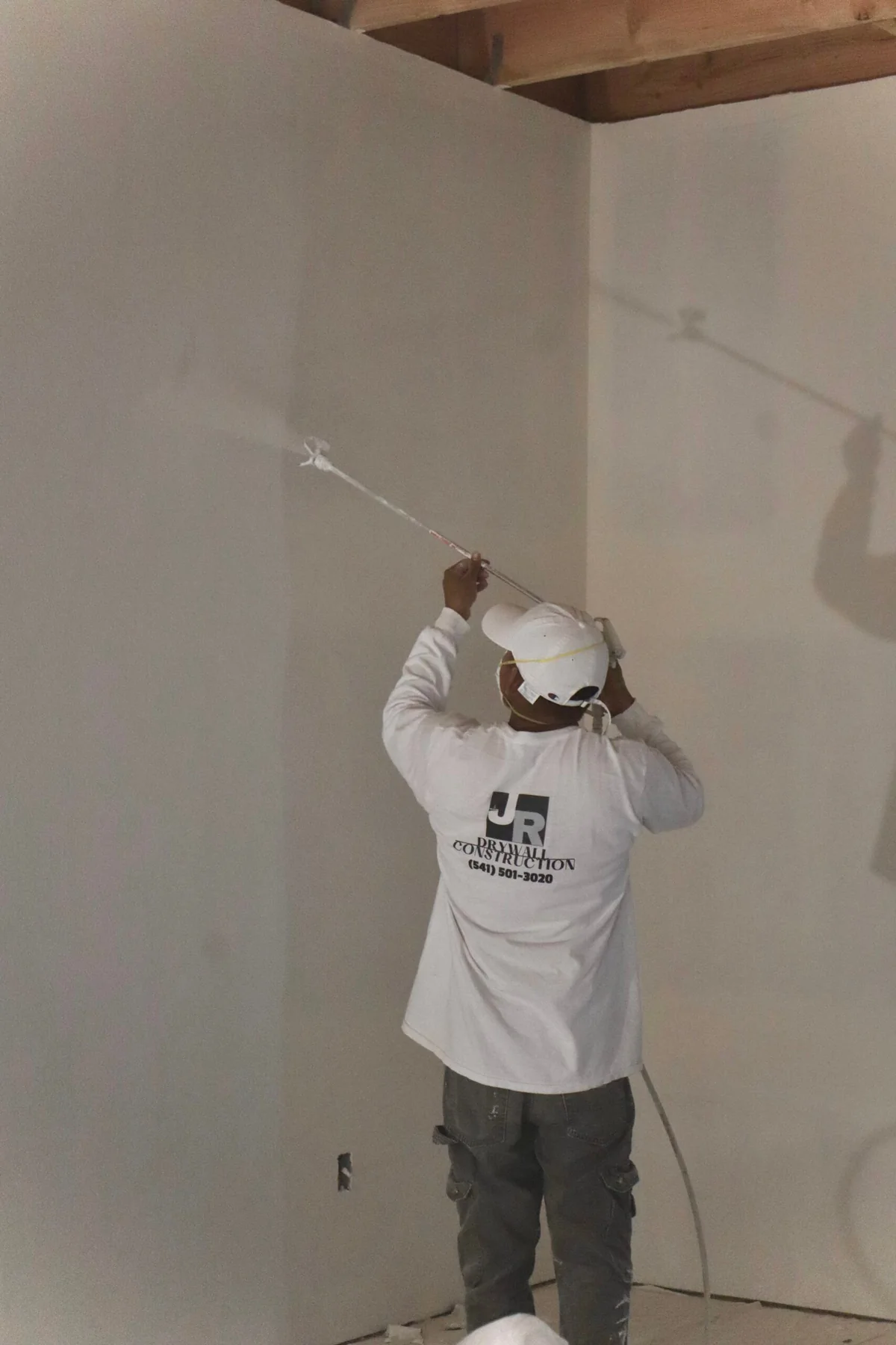 Crew member spray-texturing an interior wall
